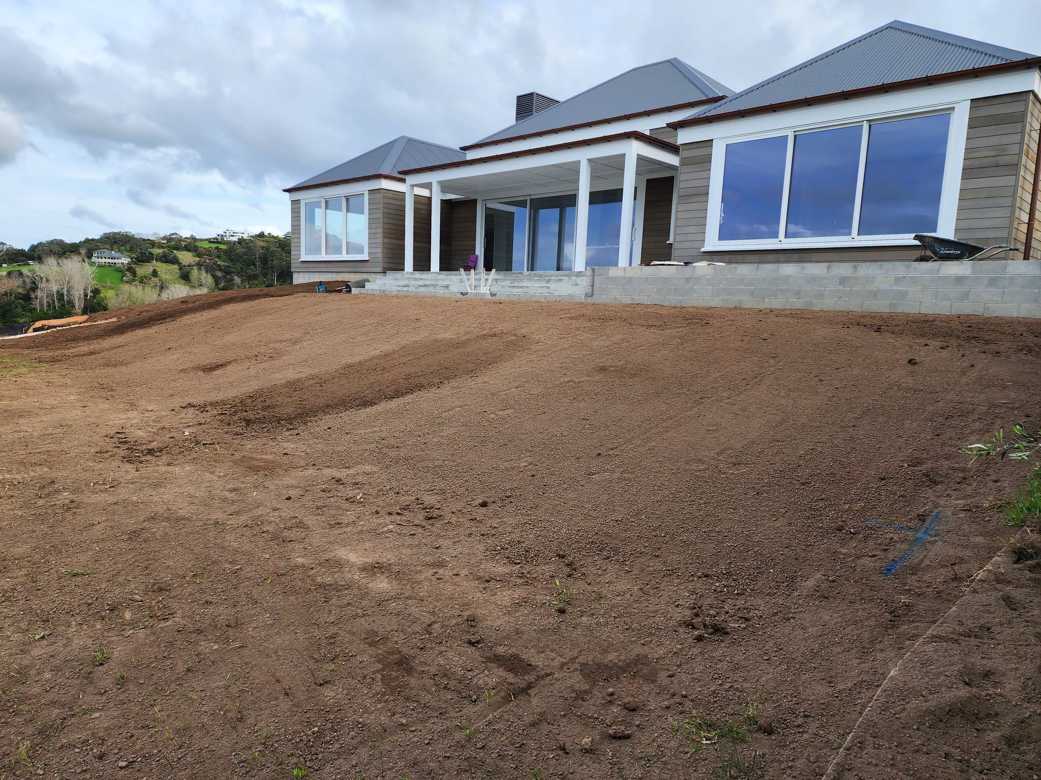 A broad graded soil area in front of a house.